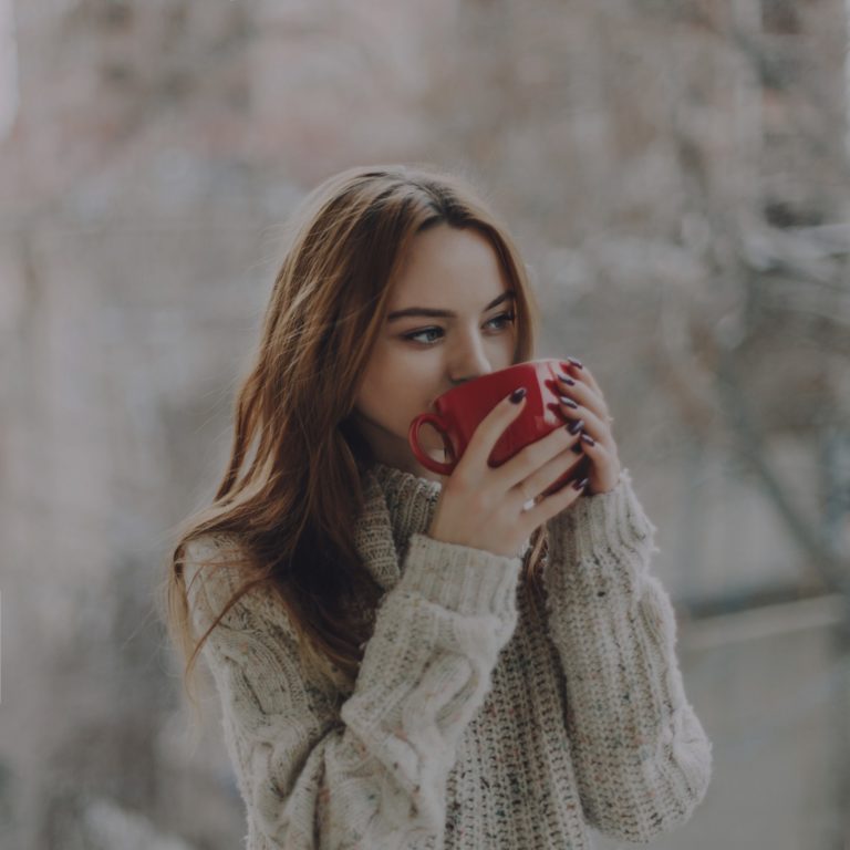 Girl in cozy sweater drinking from mug