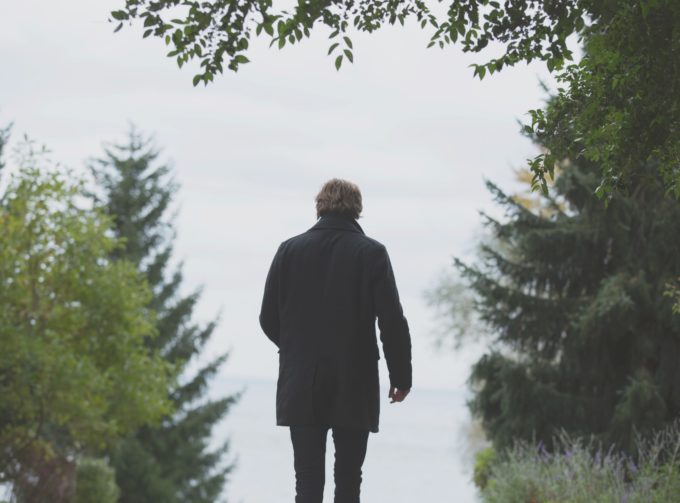 Man in coat walking through forest