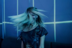 Girl dancing in blue-lit room with hair swaying in face